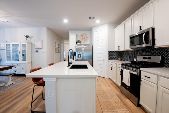 16935 Lagos Ln, Crosby, TX 77532 - kitchen with appliances with stainless steel finishes, a sink, an island with sink, backsplash, and light wood-style floors
