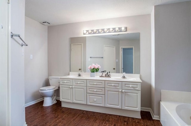 134 Willowwood Cir, The Woodlands, TX 77381 - bathroom with double vanity, toilet, baseboards, a garden tub, and wood finished floors
