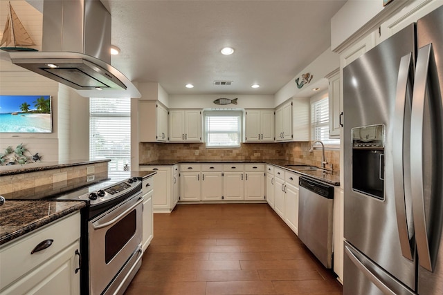 1302 Tiki Dr, Tiki Island, TX 77554 - kitchen with appliances with stainless steel finishes, island exhaust hood, a sink, decorative backsplash, and dark wood-style floors