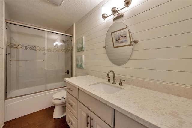 1302 Tiki Dr, Tiki Island, TX 77554 - full bath featuring a textured ceiling, vanity, wood finished floors, toilet, and combined bath / shower with glass door