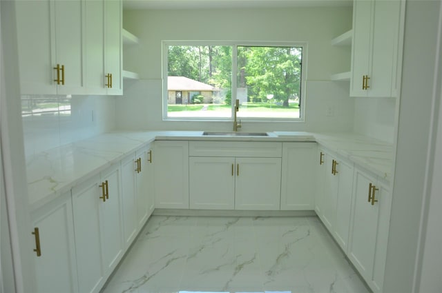 2522 Cassius Ct, New Caney, TX 77357 - kitchen featuring open shelves, light marble finish floors, white cabinets, tasteful backsplash, and light stone countertops