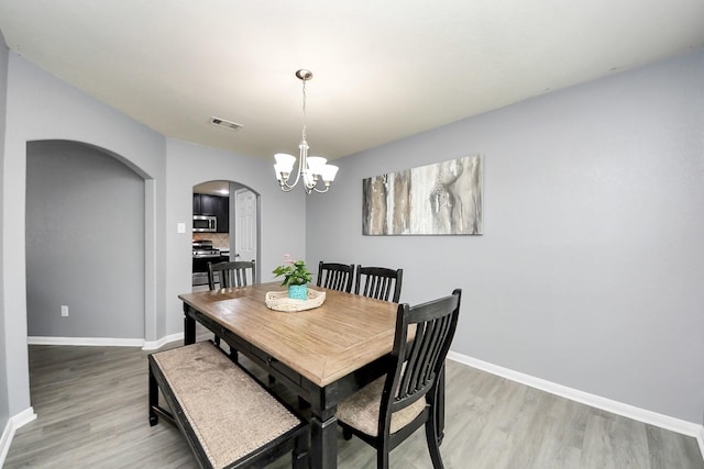 15543 Sheldon Ridge Way, Houston, TX 77044 - dining space with arched walkways, light wood-style floors, a chandelier, and baseboards
