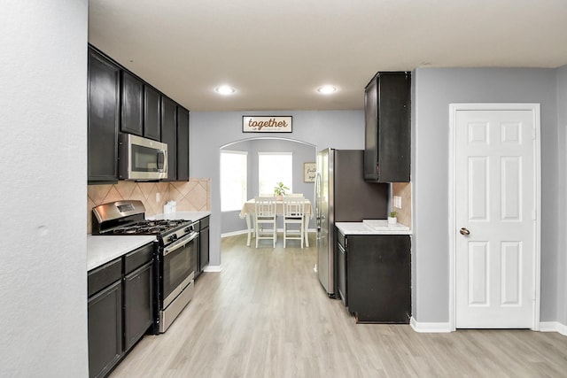 15543 Sheldon Ridge Way, Houston, TX 77044 - kitchen with appliances with stainless steel finishes, arched walkways, light wood-type flooring, light countertops, and recessed lighting