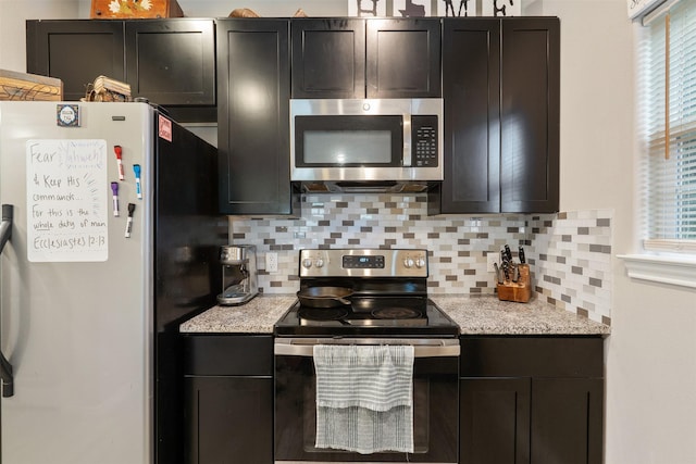 237 Ridgeside Ct, Montgomery, TX 77316 - kitchen featuring appliances with stainless steel finishes, decorative backsplash, light stone counters, and dark cabinetry