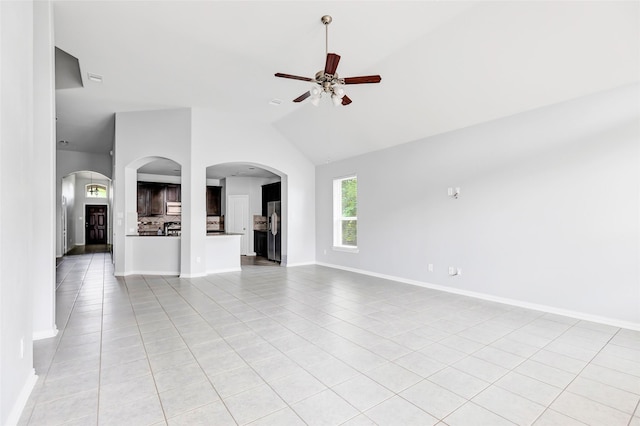 30510 Legend Oaks Ct, Magnolia, TX 77355 - unfurnished living room with a ceiling fan, light tile patterned floors, arched walkways, lofted ceiling, and baseboards