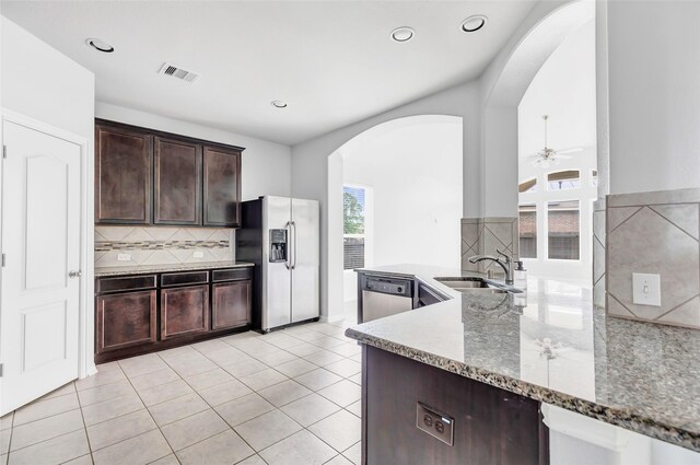 30510 Legend Oaks Ct, Magnolia, TX 77355 - kitchen with appliances with stainless steel finishes, arched walkways, light stone counters, dark brown cabinets, and a ceiling fan