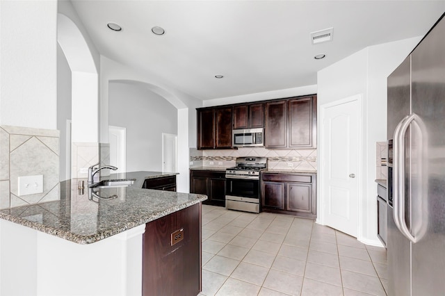 30510 Legend Oaks Ct, Magnolia, TX 77355 - kitchen with stainless steel appliances, a sink, light tile patterned floors, decorative backsplash, and stone countertops