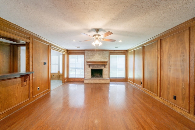 6914 Coral Ridge Rd, Houston, TX 77069 - unfurnished living room with ornamental molding, a ceiling fan, light wood-style flooring, a fireplace, and a textured ceiling