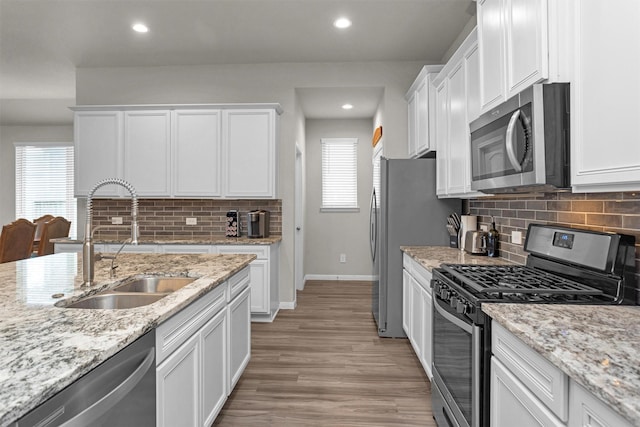 1217 Antelope Passing Dr, Montgomery, TX 77316 - kitchen featuring appliances with stainless steel finishes, a sink, white cabinetry, backsplash, and baseboards