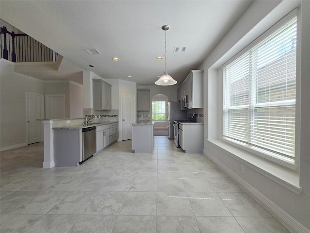 3559 Britton Burrow Way, Richmond, TX 77406 - kitchen with appliances with stainless steel finishes, a sink, gray cabinets, a kitchen island, and arched walkways