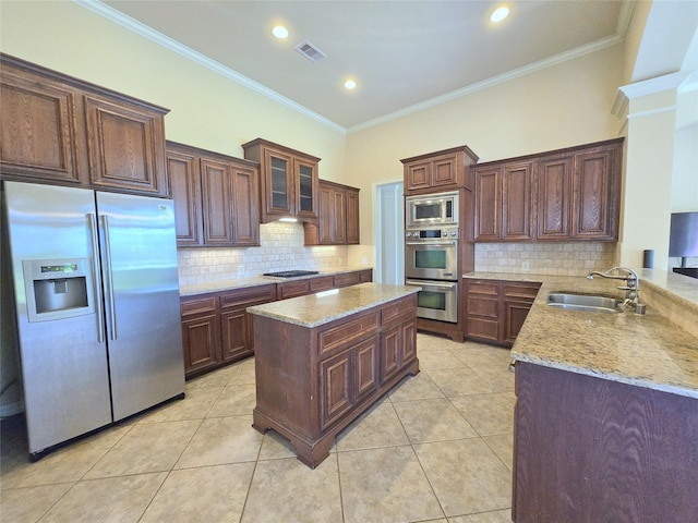 12515 Stoney Creek Dr, Pearland, TX 77584 - kitchen with appliances with stainless steel finishes, a sink, ornamental molding, tasteful backsplash, and light stone counters
