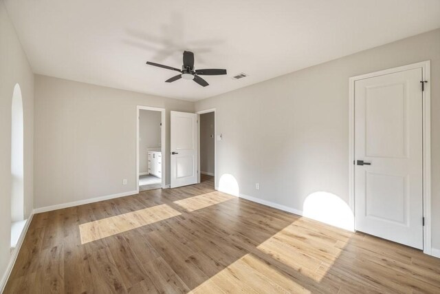 2906 Riata Ln, Houston, TX 77043 - unfurnished bedroom with wood finished floors, baseboards, arched walkways, ensuite bathroom, and ceiling fan