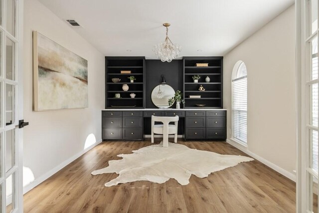 2906 Riata Ln, Houston, TX 77043 - home office featuring built in shelves, a chandelier, baseboards, and light wood-style flooring