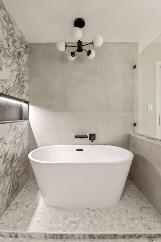 2906 Riata Ln, Houston, TX 77043 - full bath featuring tile walls, a soaking tub, a chandelier, and tile patterned flooring