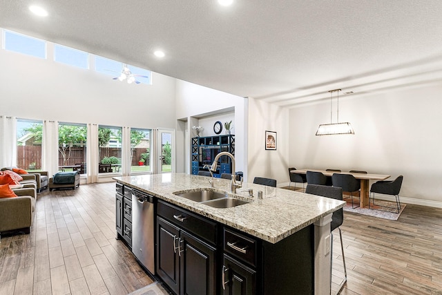 29306 Lovegrass Ct, Katy, TX 77494 - kitchen featuring open floor plan, a sink, stainless steel dishwasher, dark cabinetry, and light wood-type flooring