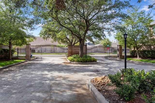 7903 S Wellington Ct, Houston, TX 77055 - view of concrete road featuring curbs, a gate, street lighting, and a gated entry