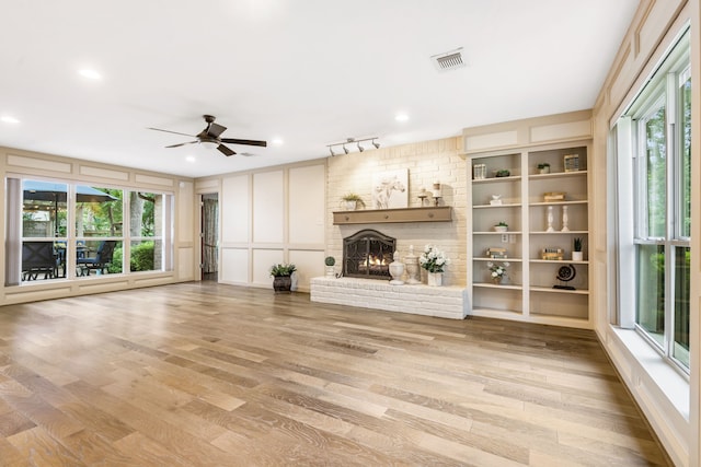 7 E Torch Pine Cir, The Woodlands, TX 77381 - unfurnished living room featuring a brick fireplace, a ceiling fan, wood finished floors, and a decorative wall