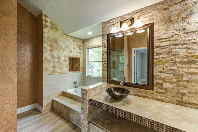 13727 Sablegarden Ln, Houston, TX 77014 - bathroom with a sink, wood finished floors, a bath, baseboards, and lofted ceiling