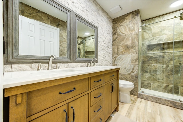 13727 Sablegarden Ln, Houston, TX 77014 - bathroom featuring tile walls, double vanity, toilet, a tile shower, and wood finished floors