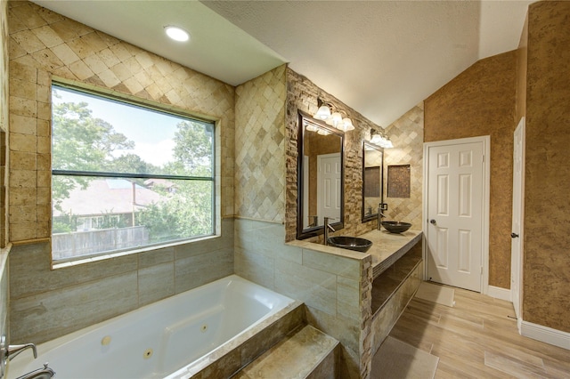 13727 Sablegarden Ln, Houston, TX 77014 - full bath featuring lofted ceiling, a tub with jets, wood finished floors, vanity, and baseboards
