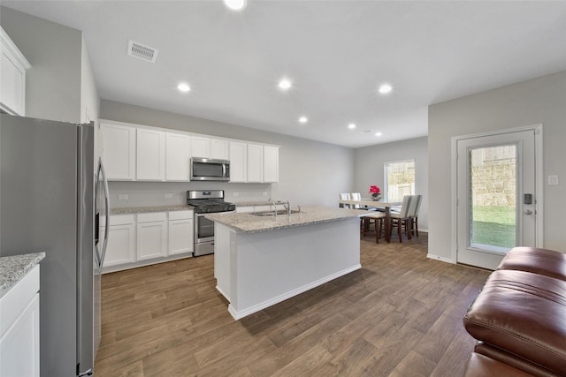 13854 Rock Island Trl, Conroe, TX 77384 - kitchen featuring appliances with stainless steel finishes, wood finished floors, a sink, recessed lighting, and white cabinetry