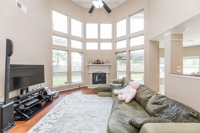 13422 Great Creek Dr, Pearland, TX 77584 - living room with a ceiling fan, wood finished floors, a glass covered fireplace, a towering ceiling, and decorative columns