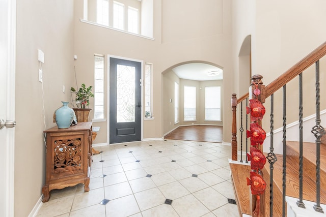 13422 Great Creek Dr, Pearland, TX 77584 - foyer with arched walkways, a high ceiling, light tile patterned flooring, baseboards, and stairway