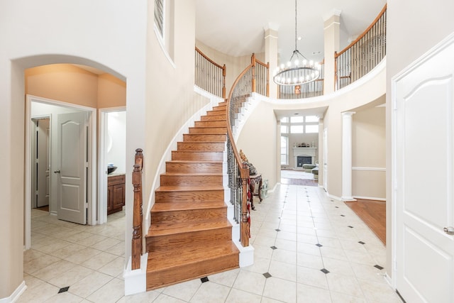 13422 Great Creek Dr, Pearland, TX 77584 - stairs with a high ceiling, tile patterned floors, arched walkways, a chandelier, and baseboards