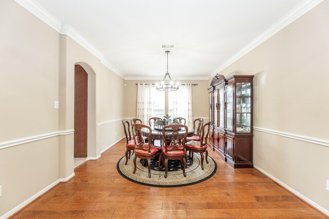 13422 Great Creek Dr, Pearland, TX 77584 - dining room with arched walkways, a chandelier, light wood-style floors, ornamental molding, and baseboards