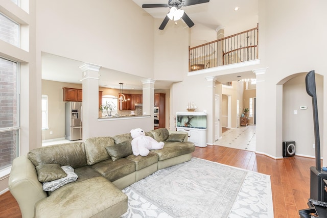 13422 Great Creek Dr, Pearland, TX 77584 - living room with a ceiling fan, light wood finished floors, ornate columns, a towering ceiling, and arched walkways