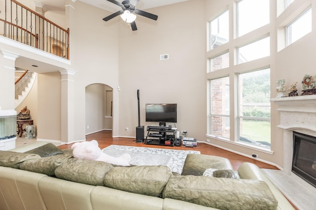 13422 Great Creek Dr, Pearland, TX 77584 - living area with a glass covered fireplace, a high ceiling, a ceiling fan, arched walkways, and wood finished floors