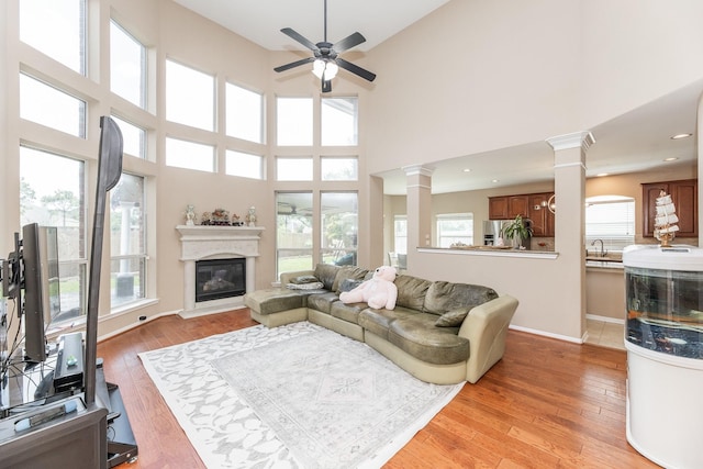 13422 Great Creek Dr, Pearland, TX 77584 - living room with decorative columns, a ceiling fan, plenty of natural light, light wood-style flooring, and a high ceiling