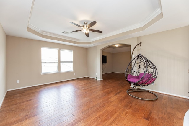 13422 Great Creek Dr, Pearland, TX 77584 - spare room featuring a tray ceiling, ornamental molding, a ceiling fan, wood finished floors, and arched walkways
