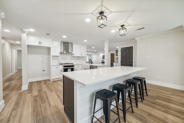 2007 Ottawa Ln, Houston, TX 77043 - kitchen featuring wall chimney range hood, white cabinets, ornamental molding, baseboards, and light wood-style flooring