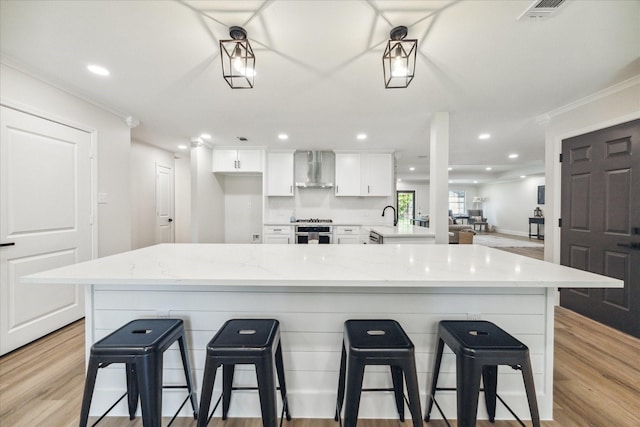 2007 Ottawa Ln, Houston, TX 77043 - kitchen with stove, wall chimney exhaust hood, white cabinetry, ornamental molding, and a kitchen bar