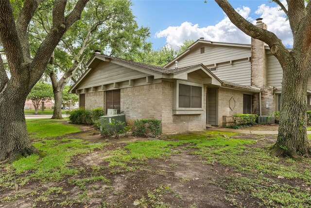 2711 Grants Lake Blvd Unit 144, Sugar Land, TX 77479 - view of front of house with brick siding, central AC, and a chimney