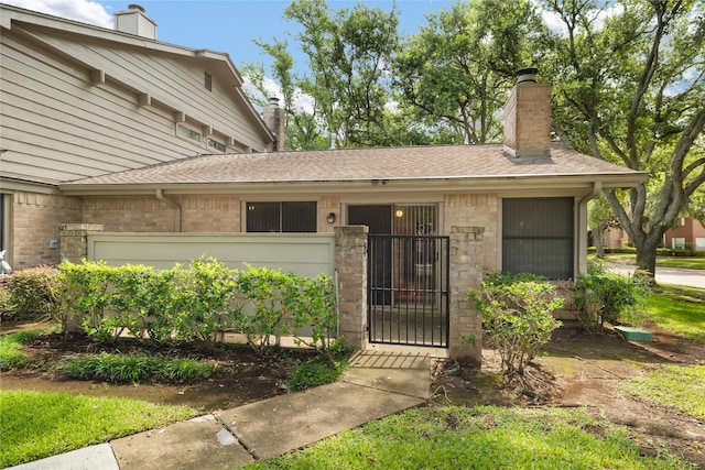 2711 Grants Lake Blvd Unit 144, Sugar Land, TX 77479 - property entrance featuring a chimney, brick siding, a shingled roof, and a gate