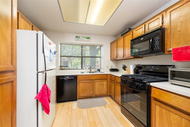 2711 Grants Lake Blvd Unit 144, Sugar Land, TX 77479 - kitchen with black appliances, a sink, light countertops, light wood-style floors, and brown cabinetry