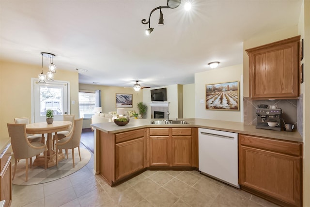 19426 Dolan Springs Dr, Tomball, TX 77377 - kitchen with white dishwasher, a tiled fireplace, a sink, a peninsula, and open floor plan
