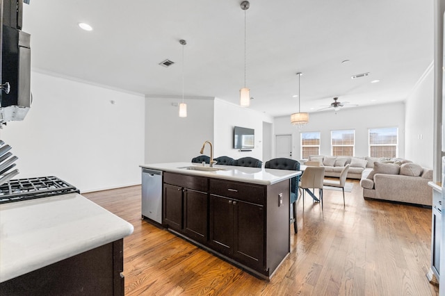 3470 Talia Wood Ct, Missouri City, TX 77459 - kitchen featuring appliances with stainless steel finishes, a sink, dark brown cabinets, light countertops, and light wood-type flooring