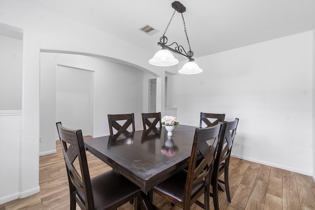9931 Chimney Swift Ln, Conroe, TX 77385 - dining room with arched walkways, light wood-style floors, and baseboards