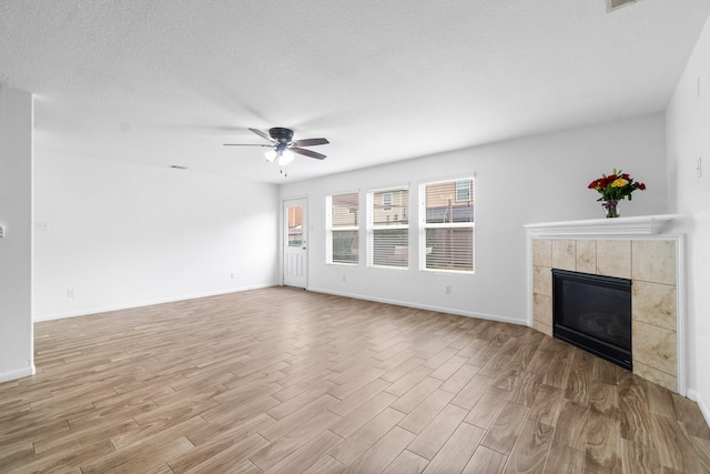 9931 Chimney Swift Ln, Conroe, TX 77385 - unfurnished living room featuring wood finished floors, a tiled fireplace, ceiling fan, and baseboards