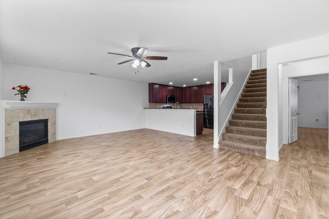 9931 Chimney Swift Ln, Conroe, TX 77385 - unfurnished living room with a ceiling fan, stairs, light wood finished floors, a tiled fireplace, and recessed lighting