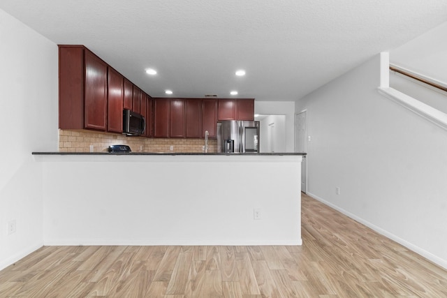 9931 Chimney Swift Ln, Conroe, TX 77385 - kitchen featuring stainless steel fridge with ice dispenser, dark countertops, reddish brown cabinets, light wood-style flooring, and recessed lighting