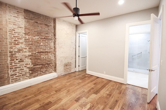 2207 Postoffice St Unit 208, Galveston, TX 77550 - unfurnished bedroom featuring baseboards, brick wall, wood finished floors, a ceiling fan, and recessed lighting