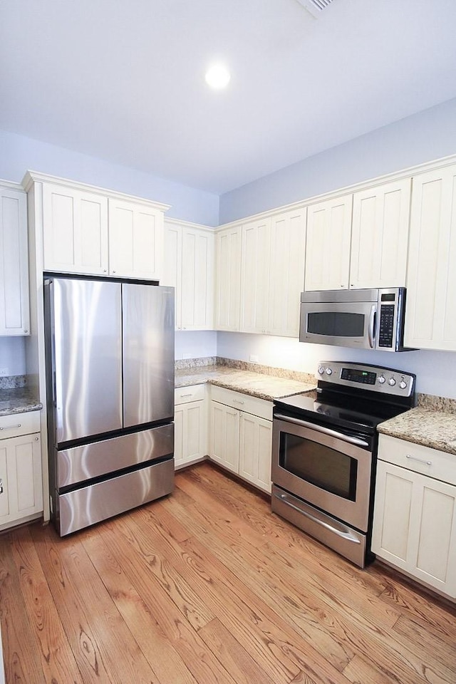 2207 Postoffice St Unit 208, Galveston, TX 77550 - kitchen with appliances with stainless steel finishes, light wood-style floors, and white cabinetry