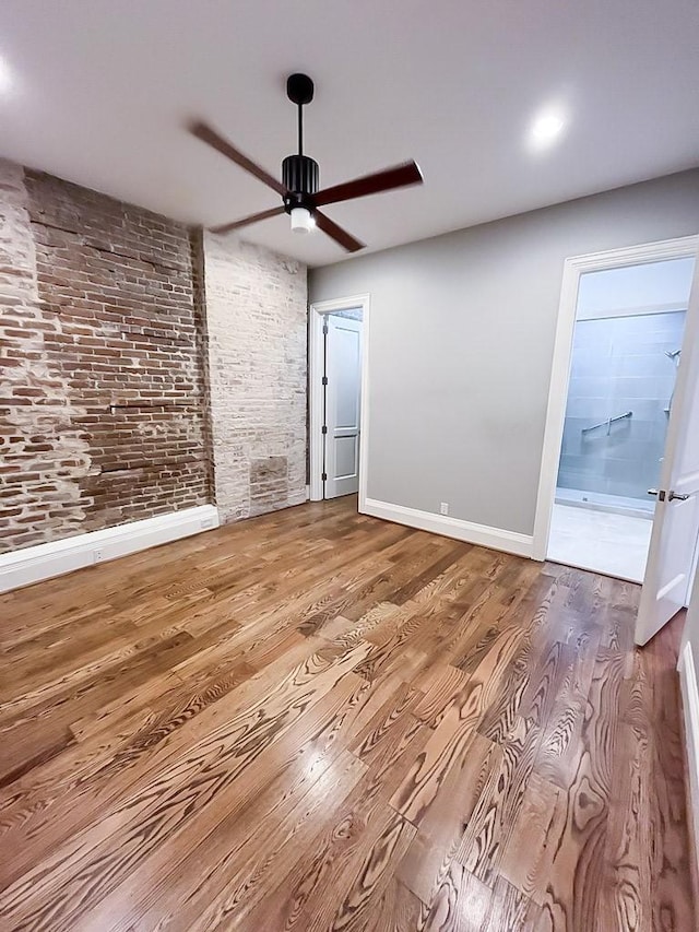 2207 Postoffice St Unit 208, Galveston, TX 77550 - empty room featuring ceiling fan, wood finished floors, baseboards, and brick wall