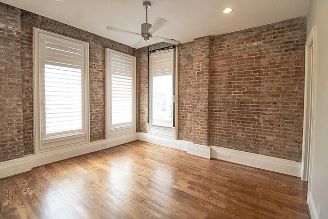 2207 Postoffice St Unit 208, Galveston, TX 77550 - unfurnished room with healthy amount of natural light, wood finished floors, baseboards, a ceiling fan, and brick wall