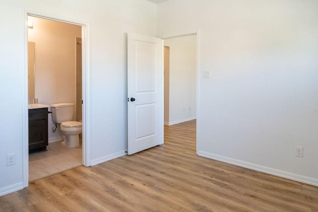 15842 Formaston Forest Dr, Humble, TX 77346 - unfurnished bedroom with light wood-style floors, connected bathroom, and baseboards