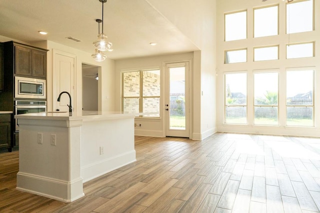 15842 Formaston Forest Dr, Humble, TX 77346 - kitchen featuring stainless steel appliances, light wood-style floors, baseboards, light countertops, and hanging light fixtures